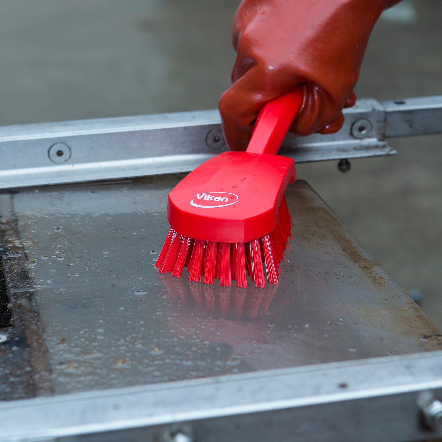 Ergonomisk vaskebørste, i rød, med kort skaft – fjerner genstridigt snavs fra transportbånd, maskiner og overflader i fødevareproduktion.
