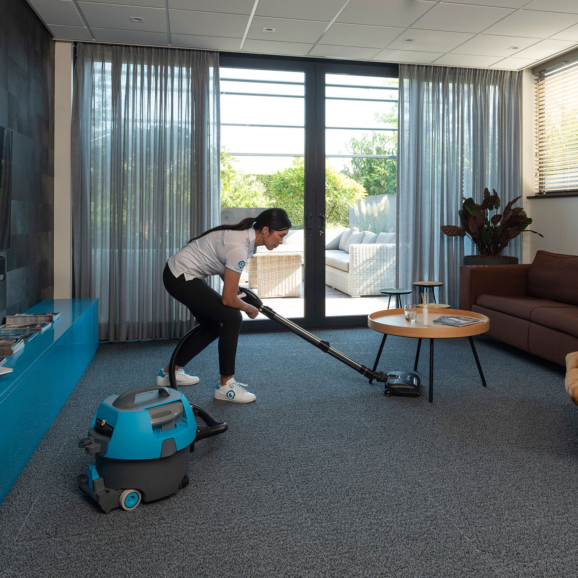 i‑vac 5 professionel støvsuger med ergonomisk bærehåndtag, fleksibel slange, teleskoprør og 8 meters aftagelig ledning. Støvsugeren er vist i et hotel miljø. Den har 5-liters støvposekapacitet og praktiske integrerede redskabsholdere.