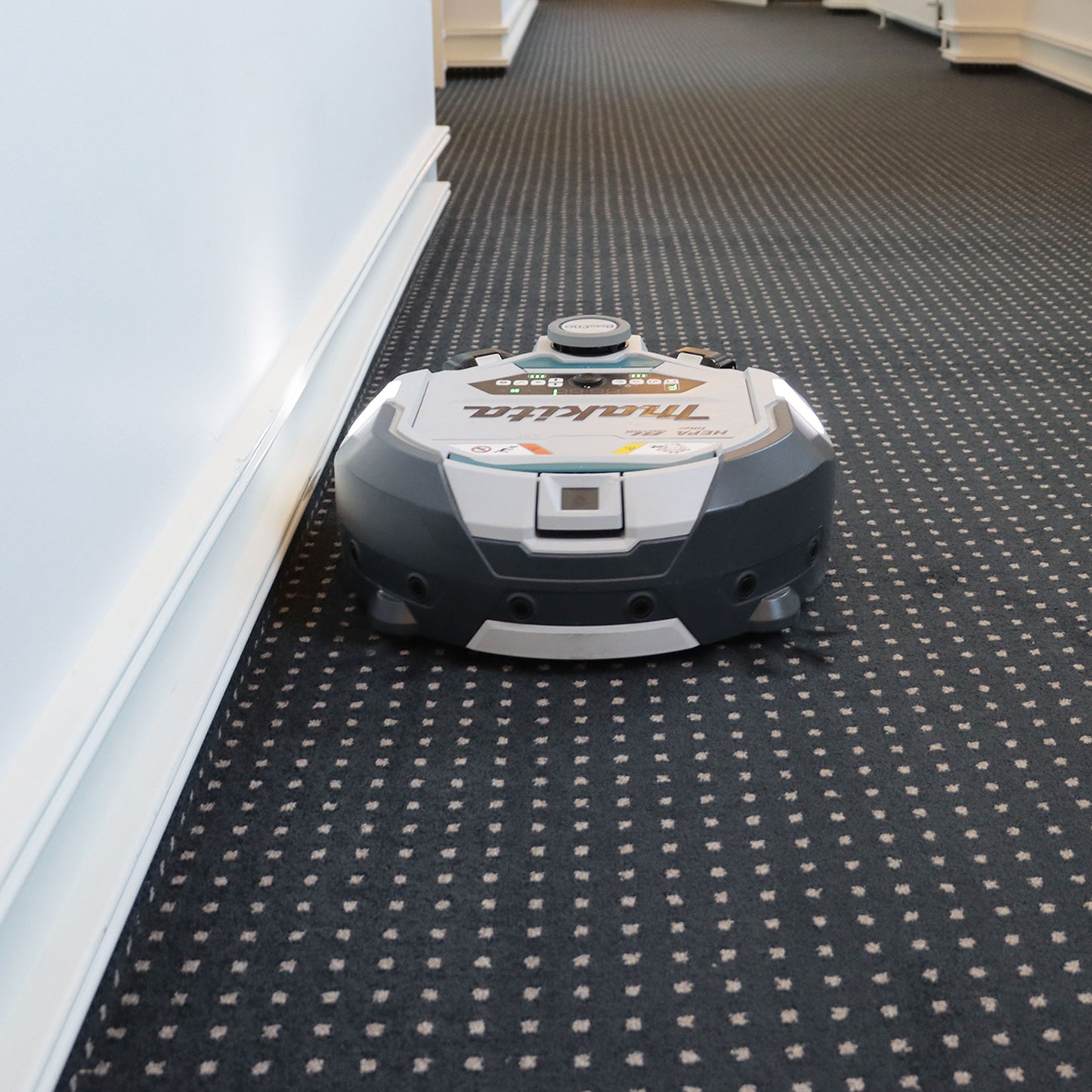 Robotstøvsuger foran på mønstret tæppe, set lige forfra