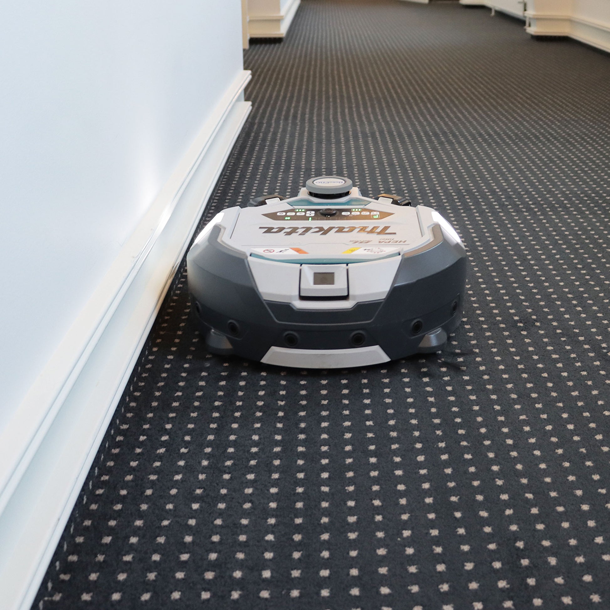 Robotstøvsuger foran på mønstret tæppe, set lige forfra